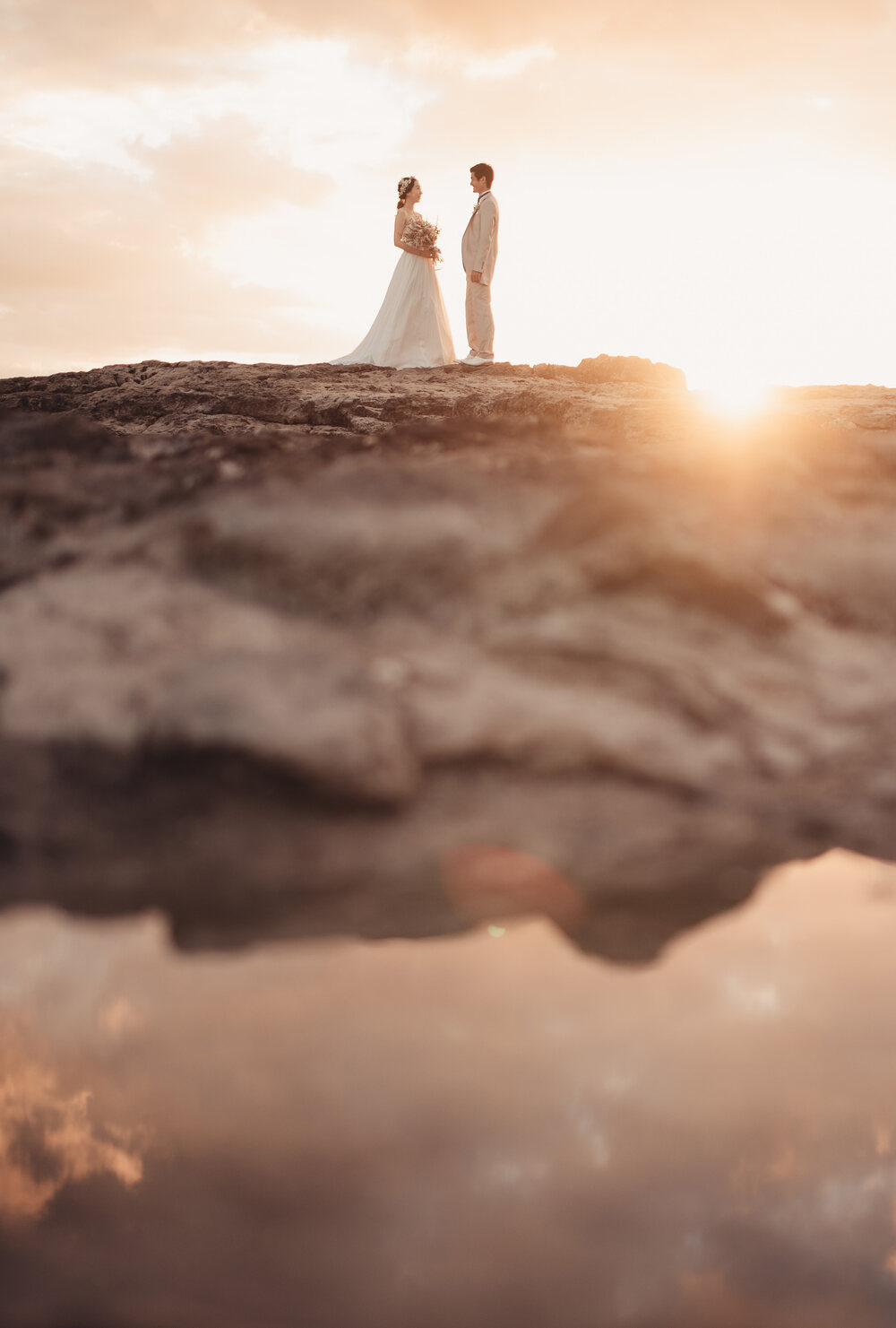 Newlyweds standing together at sunset